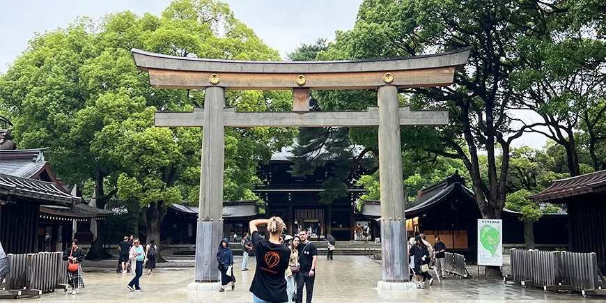 Nainen ottaa kuvan pariskunnasta torii-portin alla Meiji-pyhäkössä