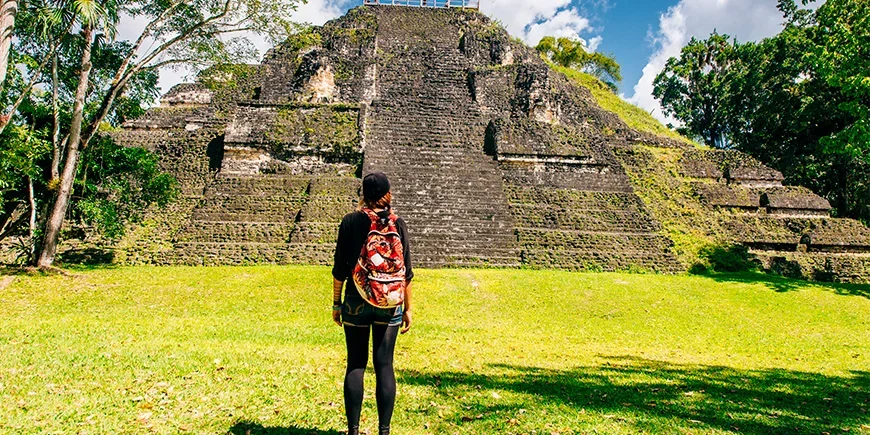 Nainen seisoo pyramidin edessä Tikalin kansallispuistossa 